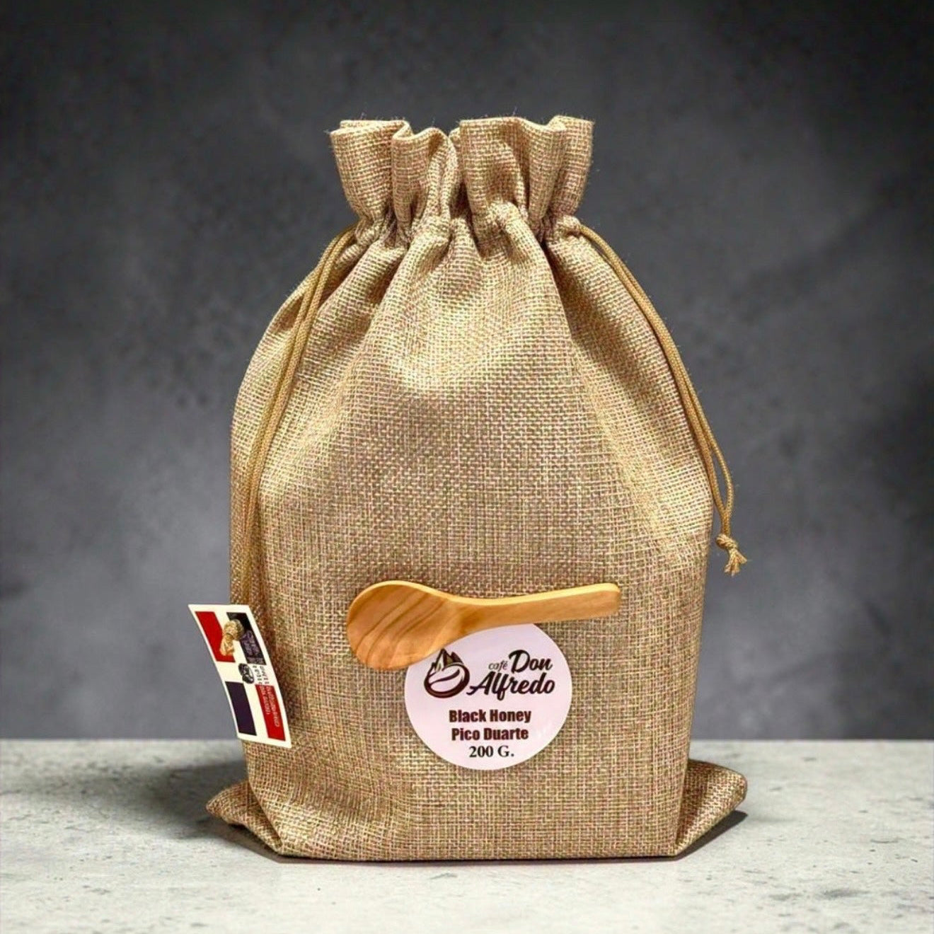 Hessian drawstring bag with a wooden spoon and label on a gray background